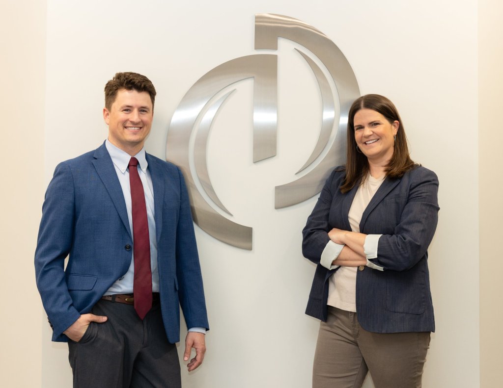 Dr. White and Dr. Gulis smiling with Integrity Dental Care logo hanging on wall